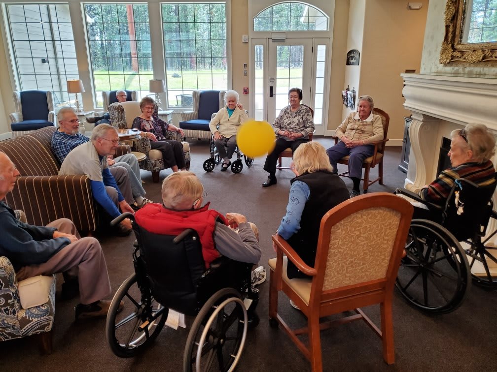 A group of seniors participating in a ball game inside a community room.
