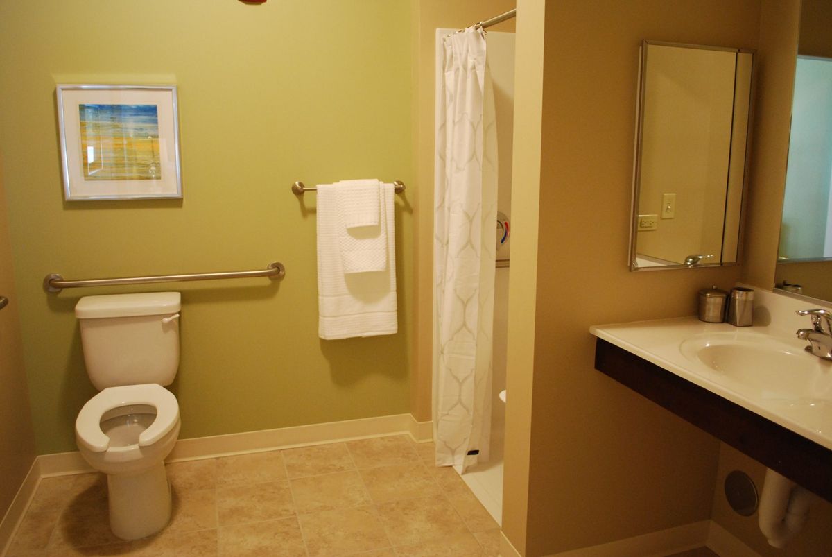 A modern bathroom featuring a toilet, shower, and a neatly hung towel.