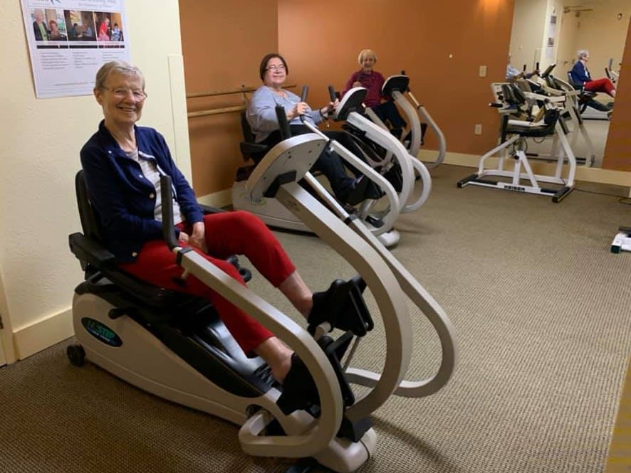 Seniors enjoying a workout on exercise bikes at the gym.
