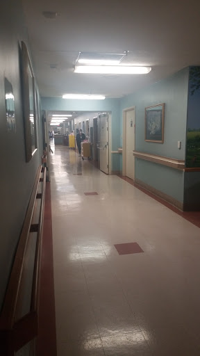 A view of a hospital hallway with patient rooms and clean floors.