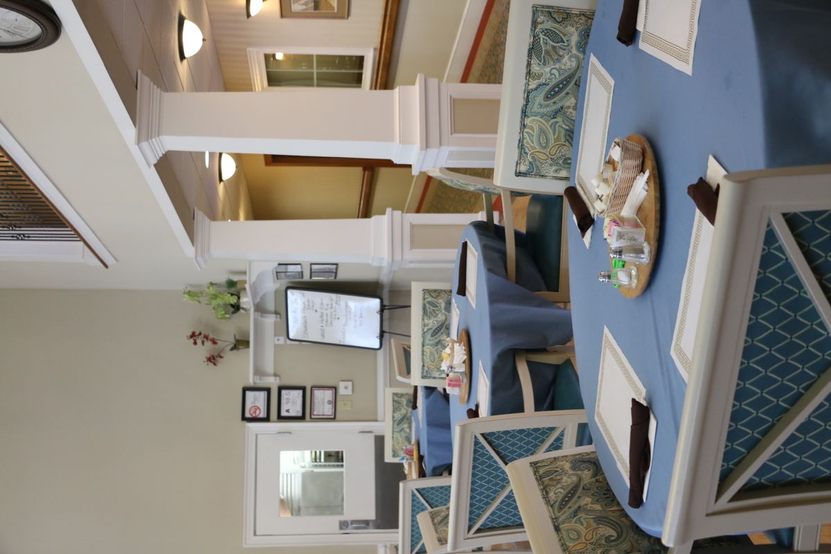 A cozy dining area with neatly arranged tables and chairs, featuring elegant decor and pillars.