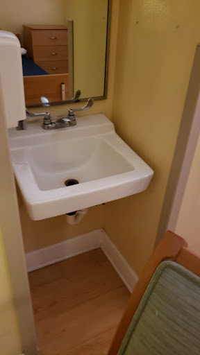 A compact white sink installed in a bathroom with yellow walls.