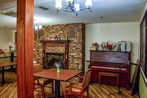 A cozy living space featuring a brick fireplace, a piano, and a dining area.