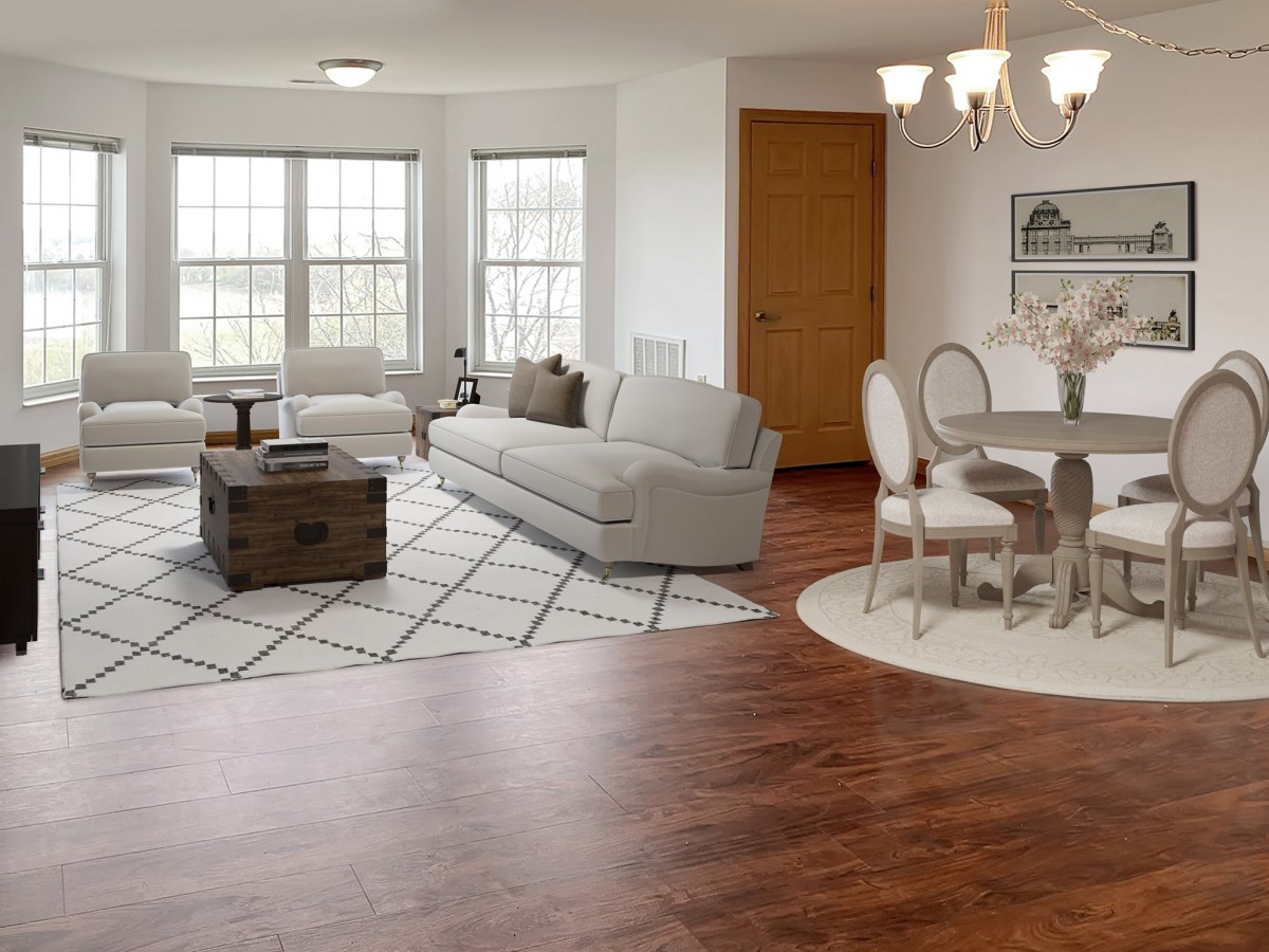 A cozy living and dining space with wood flooring, featuring a gray sofa, circular dining table, and elegant chandelier.