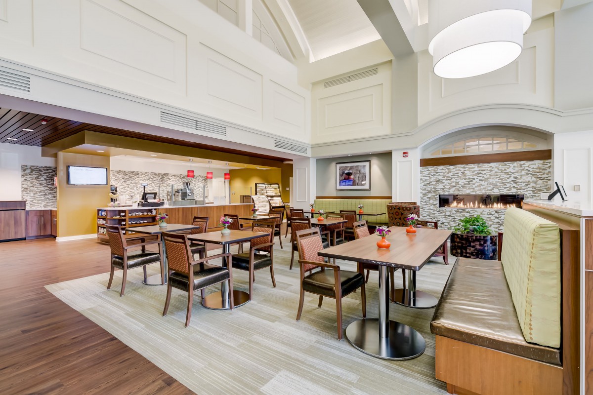 A cozy and modern dining area with neatly arranged tables and chairs, featuring ambient lighting.