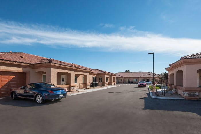 A view of residential buildings with a parking lot under a clear blue sky.