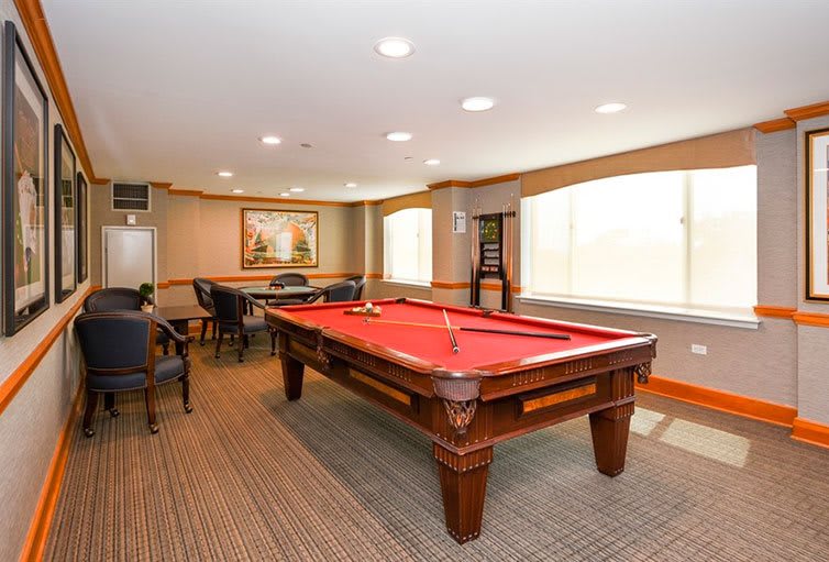 A cozy game room featuring a red-felt pool table and seating area.