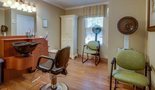 A cozy hair salon interior with chairs, a mirror, and a hair dryer on a wooden floor.