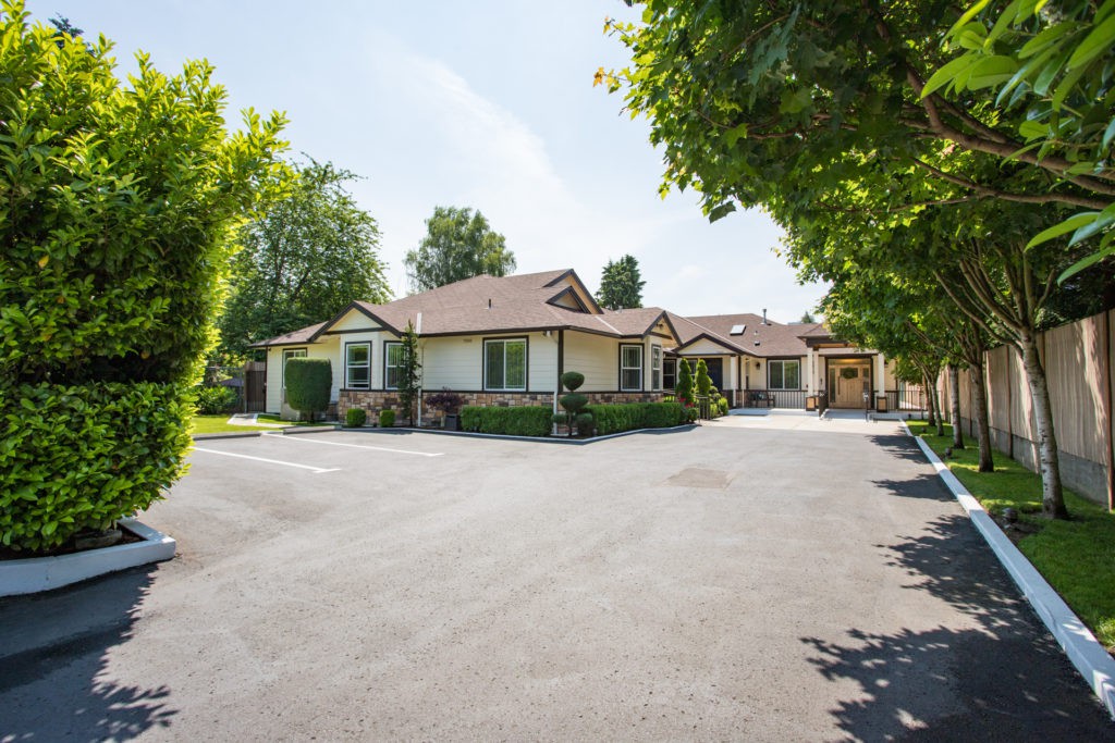 A suburban house with a spacious driveway surrounded by trees.
