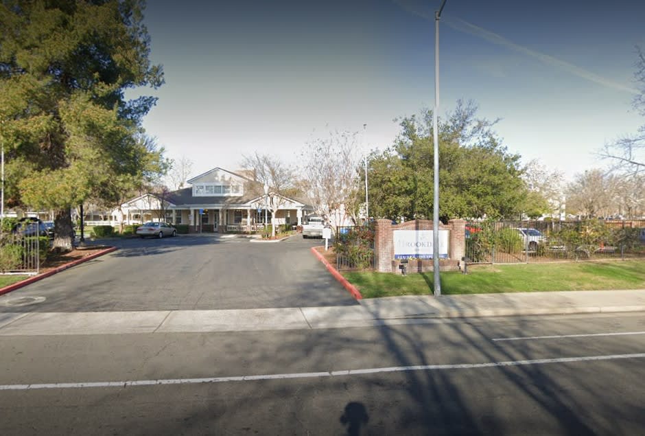 A suburban building with a parking lot and trees along the road.