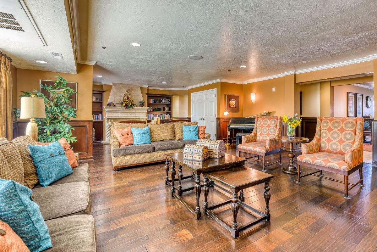 A spacious and elegantly decorated living room featuring a mix of comfortable seating, wooden flooring, and a cozy fireplace.