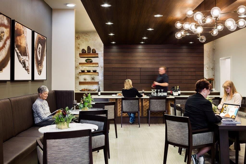 A cozy cafe interior with modern design, featuring several people seated at tables and a bar area.