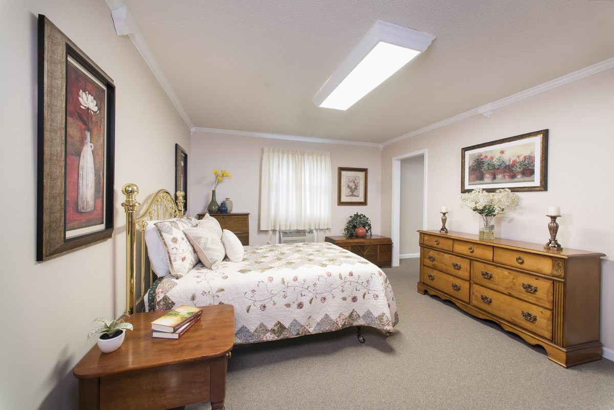 A well-furnished bedroom with a bed, dresser, and nightstand.