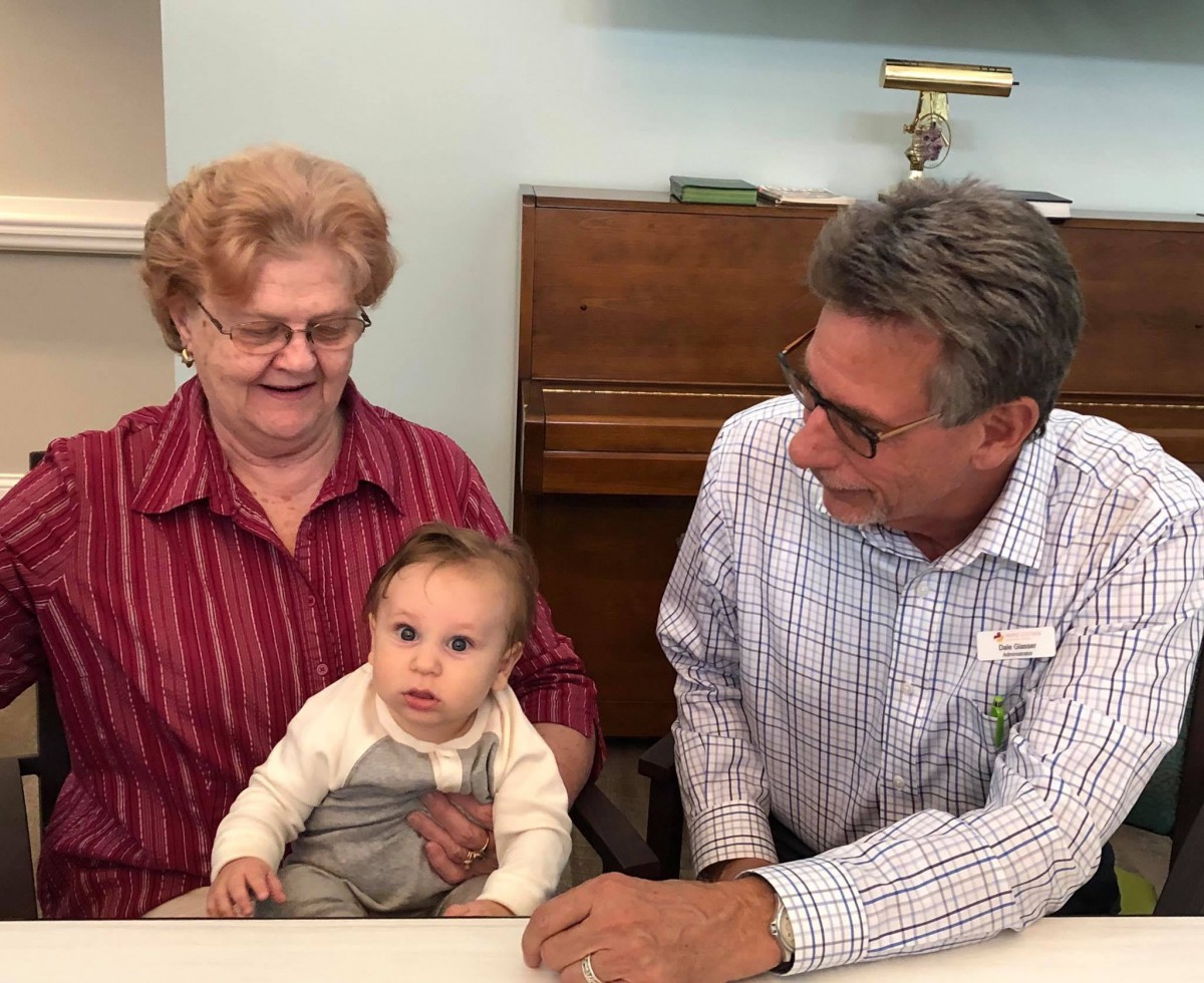 An elderly woman and a man sitting at a table with a baby.