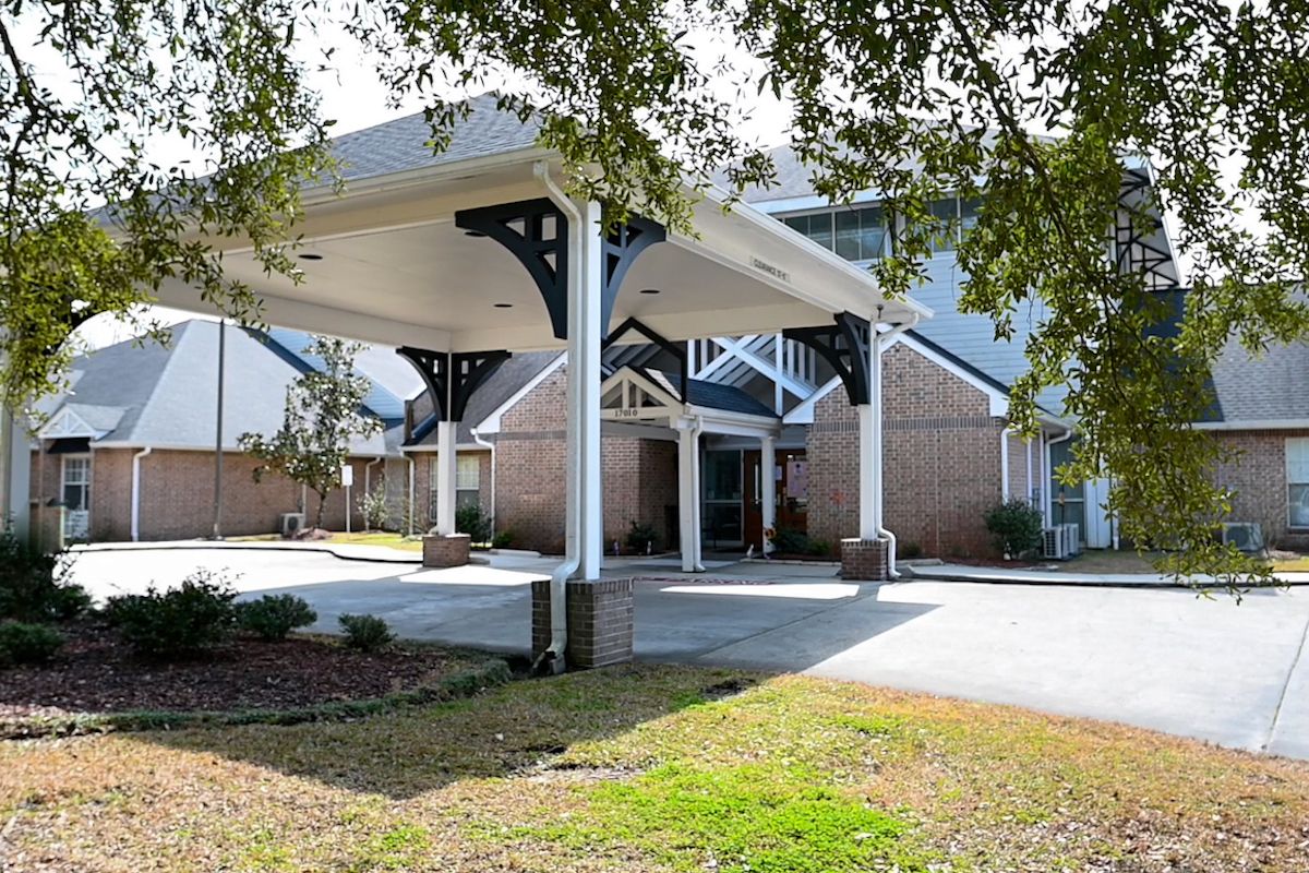 A building entrance with a covered canopy and surrounding landscaping.
