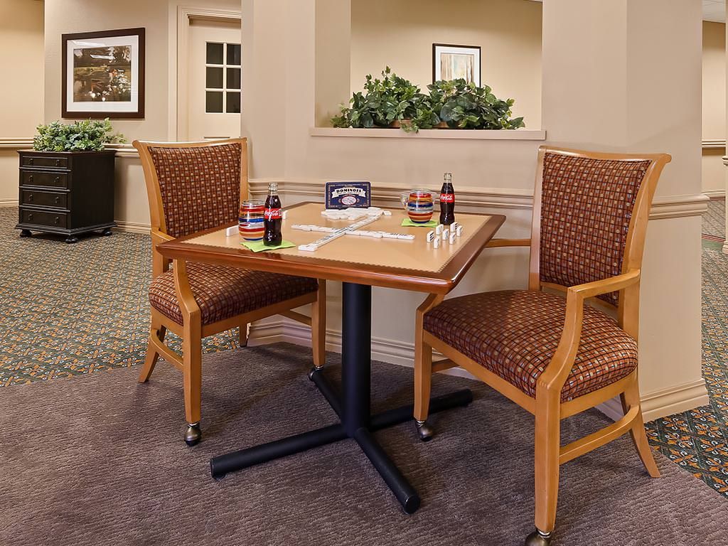 A dining table set with two chairs in a cozy indoor setting, featuring two Coca-Cola bottles.