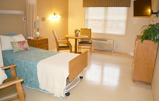 A bright and clean hospital room with a bed, table, and chairs.