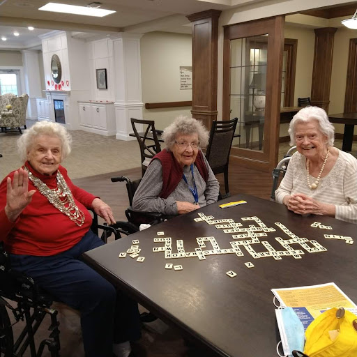 A group of three senior women enjoying a game of dominoes together in a community center.