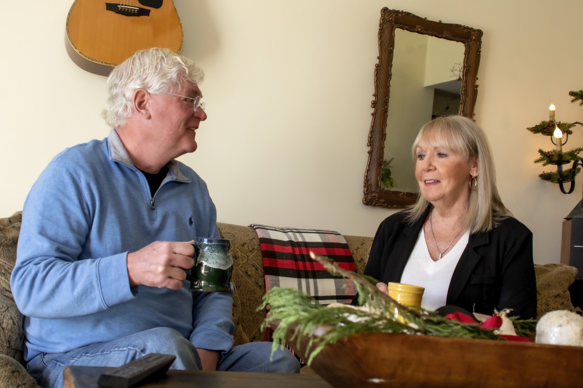 Two people having a conversation over tea in a cozy living room.