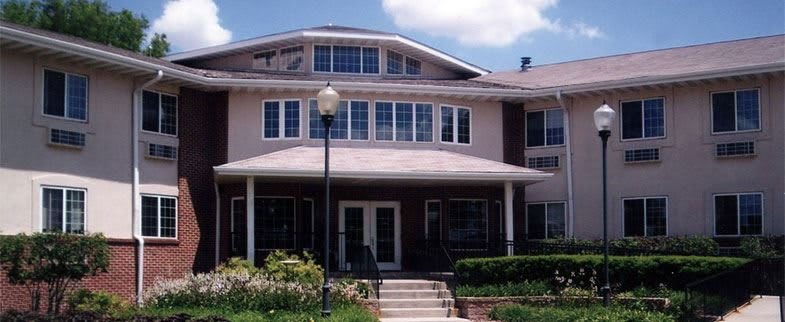 A two-story residential building with a landscaped entrance and multiple windows.