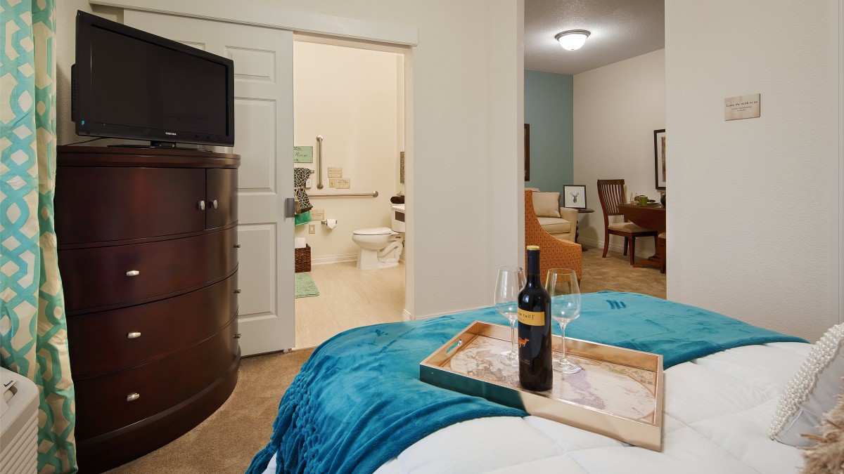 A cozy bedroom with a view into the bathroom, featuring a wine bottle on a tray for a touch of luxury.