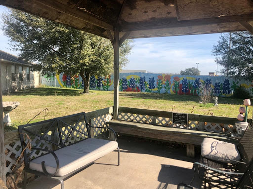 A peaceful gazebo view overlooking a colorful fence and lush greenery.