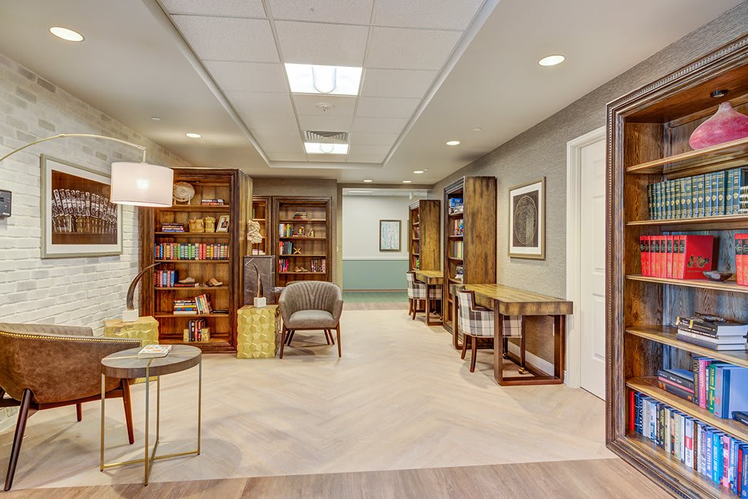 A cozy library reading area with bookshelves, comfortable chairs, and tables.