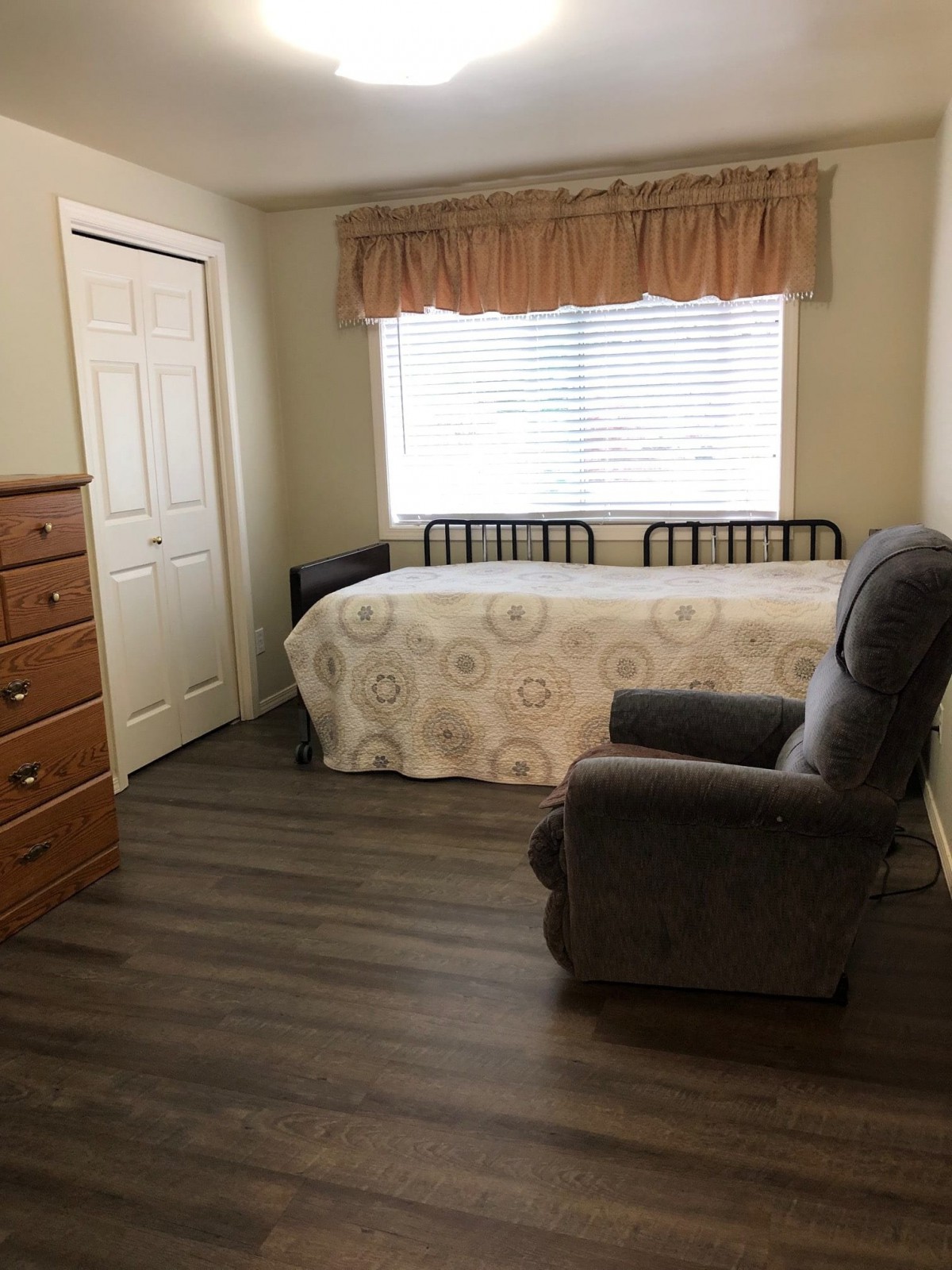 A cozy bedroom with a single bed and an armchair next to the window.