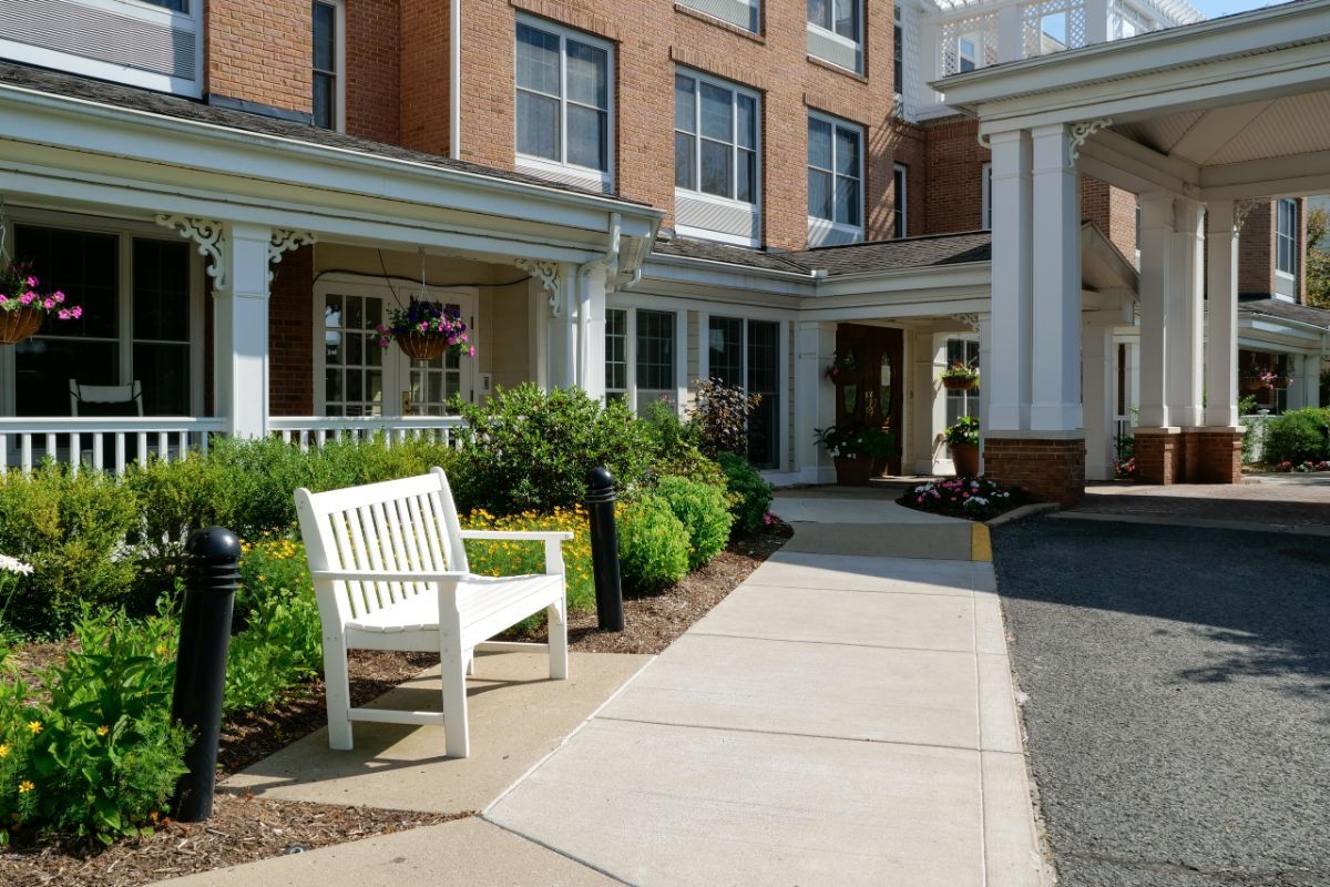 The entrance to a building featuring a white bench and well-maintained landscaping.
