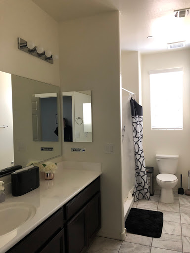 A modern bathroom featuring a clean design with mirrors, a shower area, and natural lighting from the window.
