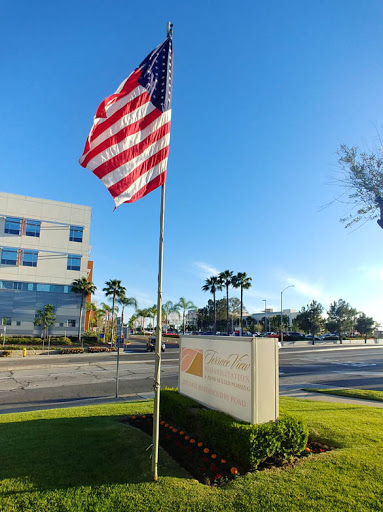 A clear day featuring the American flag in front of a modern building.