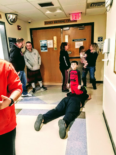 A group of people, including children, interacting in a hospital hallway.