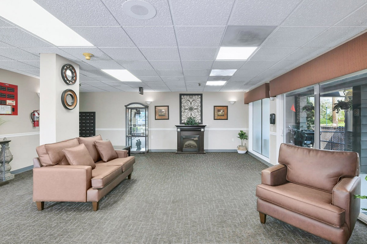 A spacious lobby featuring comfortable seating with sofas and an armchair, adorned with art pieces and a glass display case.
