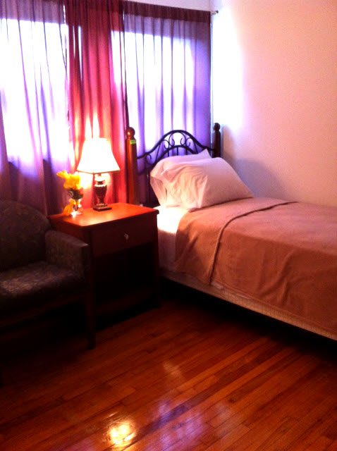Cozy bedroom with a single bed, nightstand, and lamp.