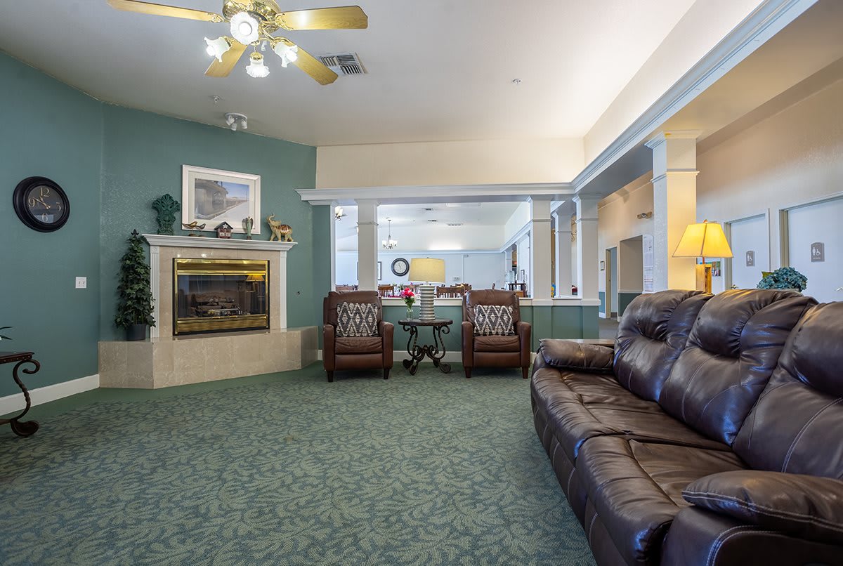 A cozy living room with a fireplace, comfortable seating, and a ceiling fan.