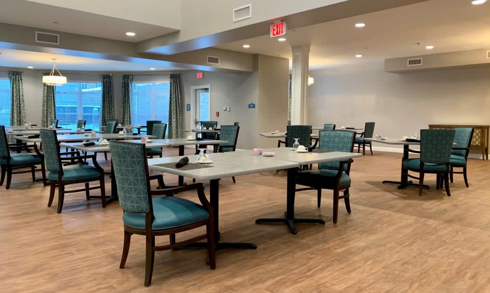 An empty dining area with neatly arranged tables and chairs on a wooden floor.