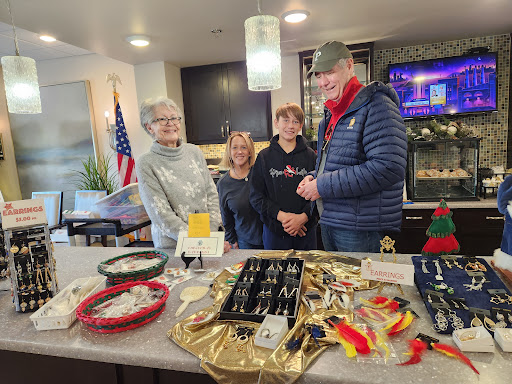 A group of individuals gathered around a table displaying various jewelry items during a community event.