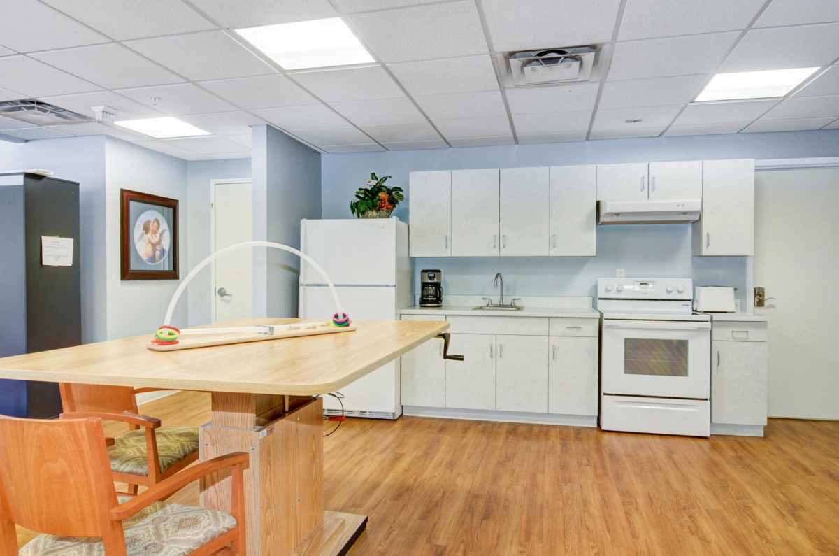 A modern kitchen interior with white cabinets and wooden flooring.