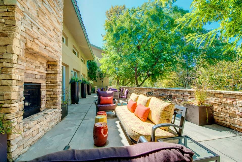 A sunny outdoor patio with comfortable seating and lush greenery.