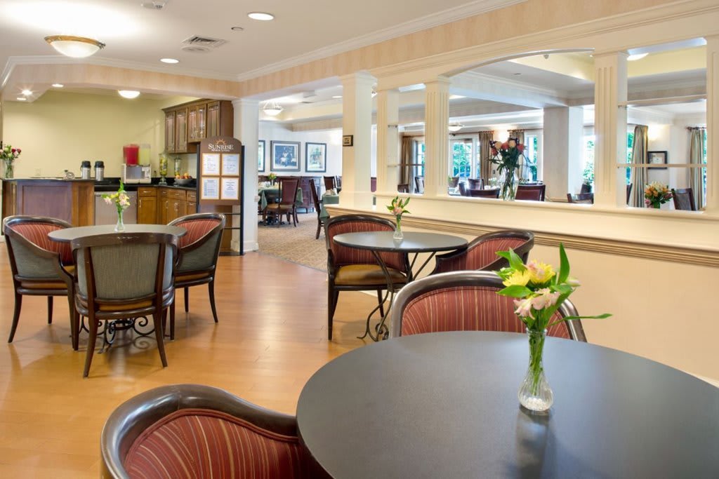 A cozy dining area with tables, chairs, and floral decorations.