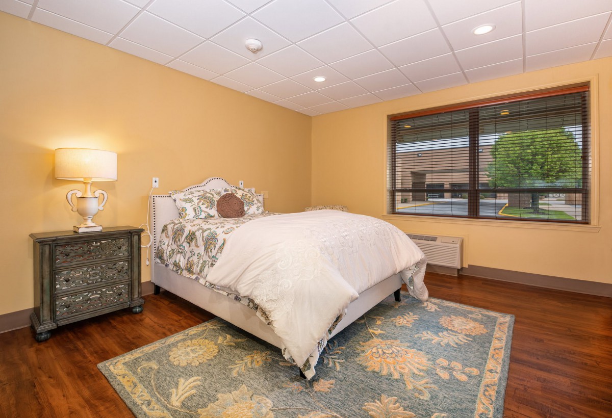 A cozy bedroom with a single bed and a decorative carpet.