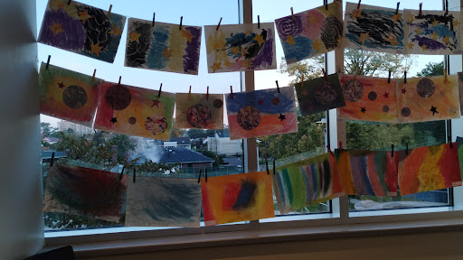 A vibrant display of children's artwork hanging by the window.