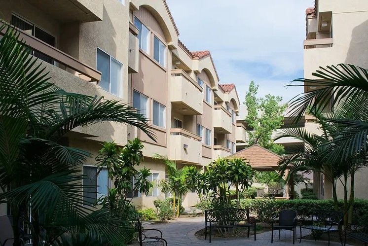 A view of a residential apartment complex with well-maintained landscaping and palm trees.