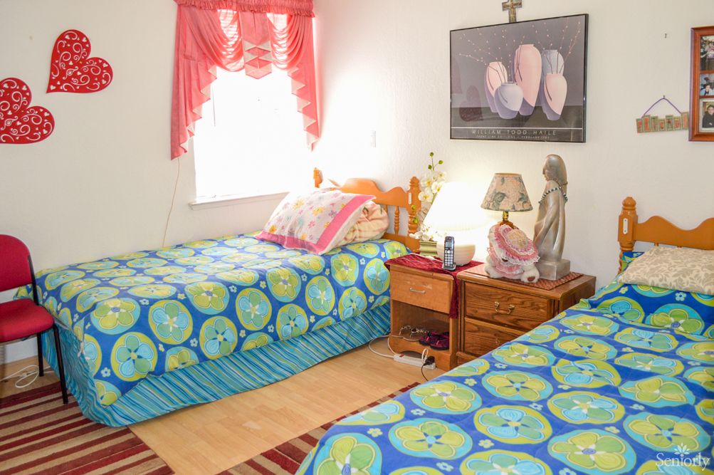 A cozy bedroom with twin beds featuring bright, colorful bedding and a warmly lit nightstand.
