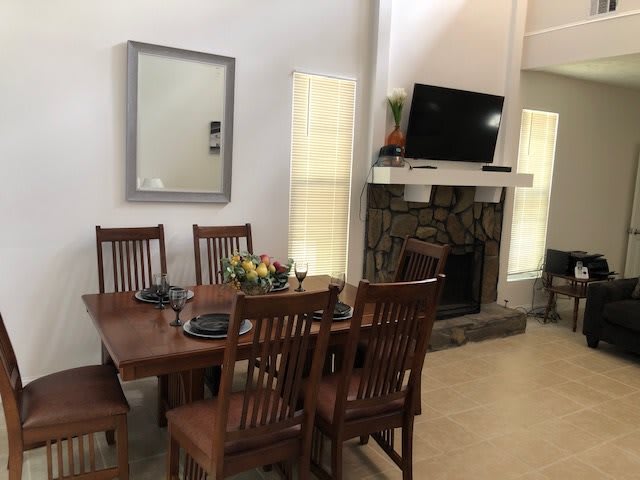 A cozy dining area with wooden furniture, featuring a table and chairs next to a fireplace and TV.