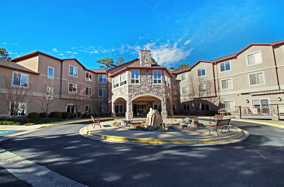 A large residential building with a stone facade and an inviting entrance under a clear blue sky.
