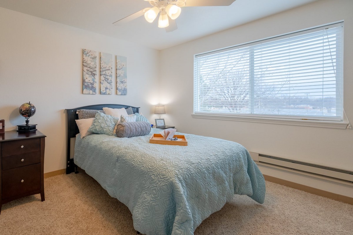 Cozy bedroom with blue bedding and a ceiling fan.