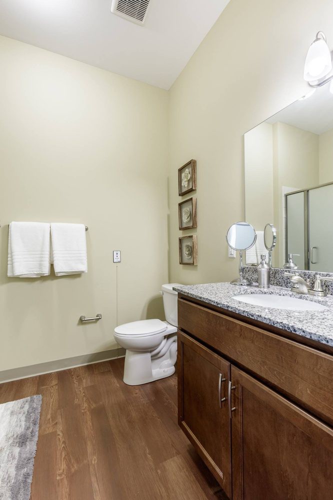 A clean and modern bathroom with a large mirror, sink, and neatly arranged towels.