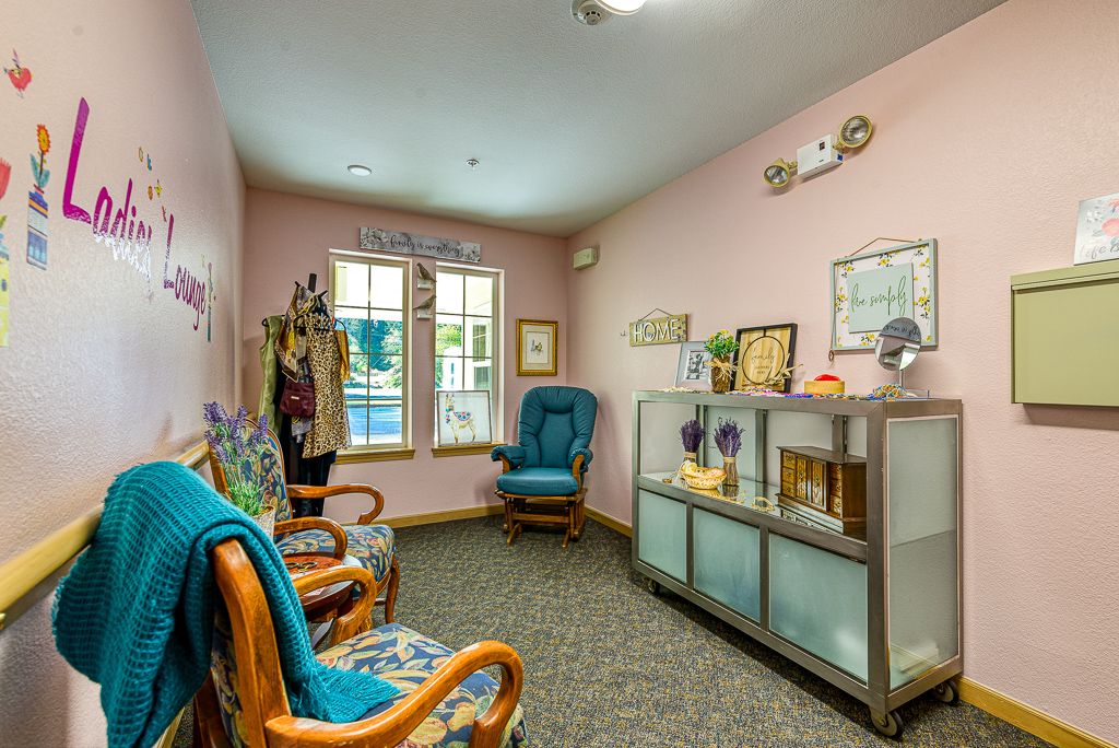A cozy room featuring upholstered chairs, a shelving unit, and vintage decor.