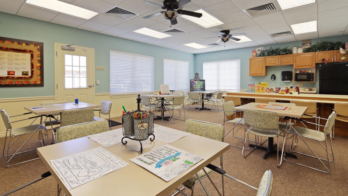 A well-lit classroom with tables and chairs arranged for group activities and learning.
